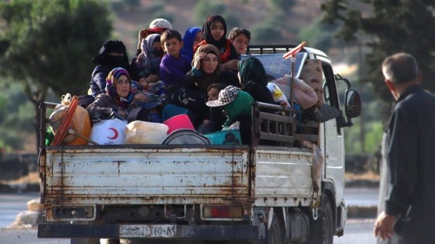 Displaced Syrians sit in the back of a lorry as they flee along the M4 highway, in Ariha, Idlib province (8 June 2020)