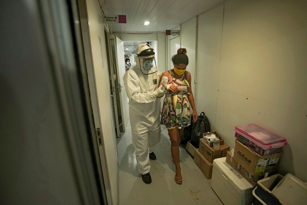 A worker from the Special Secretariat for Indigenous Health assists 19-year-old Janete Vasconcelos da Silva, an indigenous woman from the Tupinamba tribe and 8 months pregnant and who has been diagnosed with the novel coronavirus, after bringing her to a hospital in Santarem, Para State, Brazil on July 17, 2020.