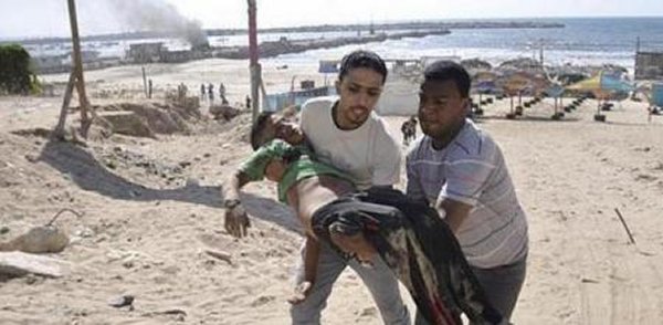 Un hombre carga con un niño herido por un ataque israelí mientras jugaba al fútbol con sus amigos en una playa de Gaza
