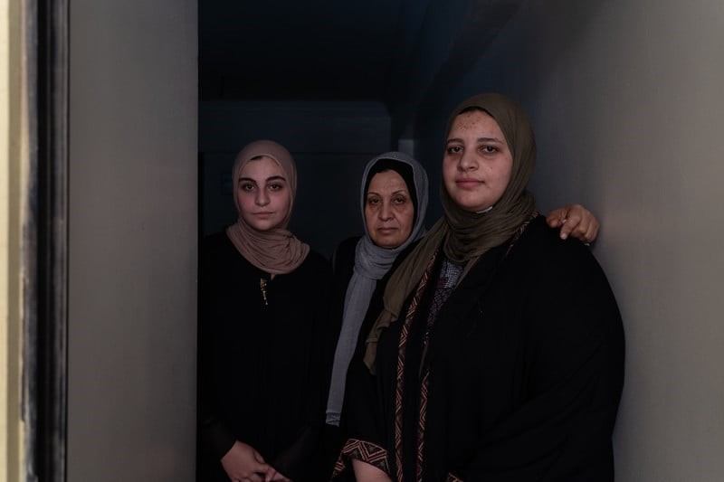 Tres mujeres están de pie en el umbral de una puerta